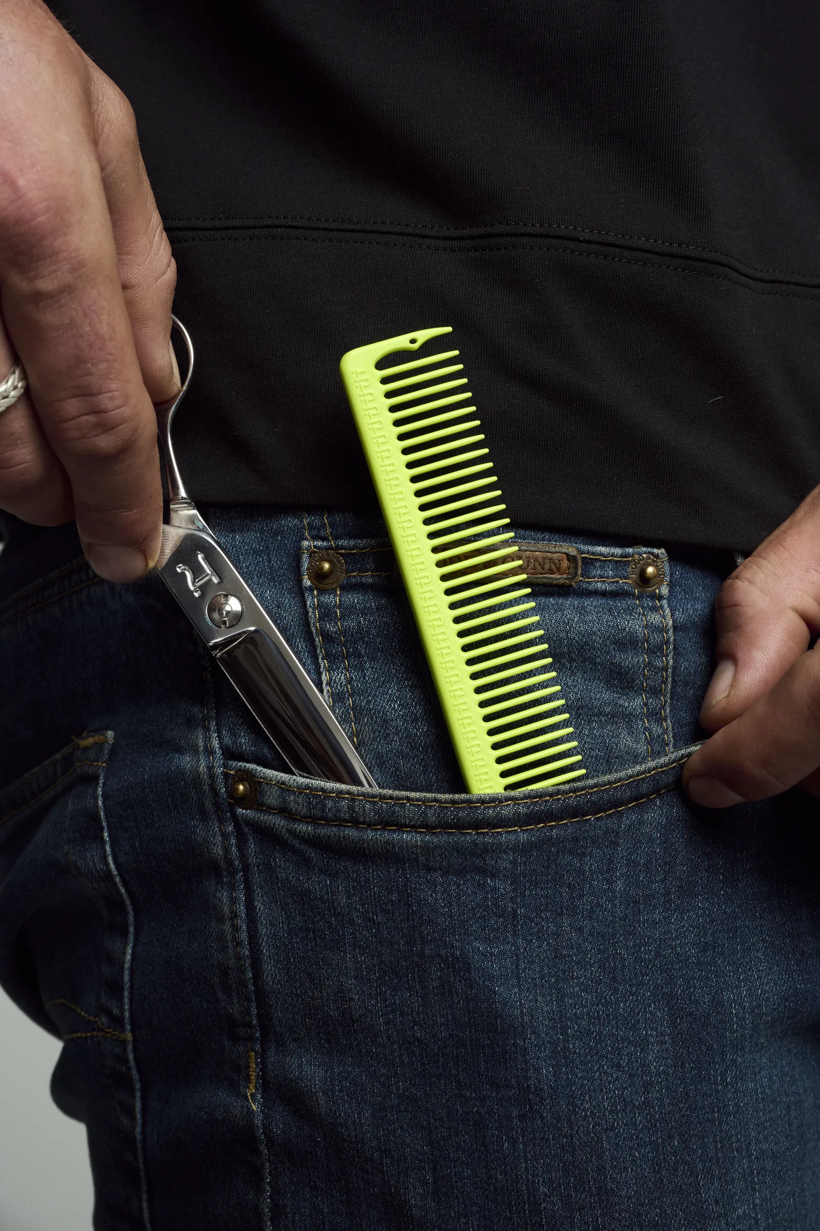 Hanzo shears and a neon green Hanzo comb in a jeans pocket